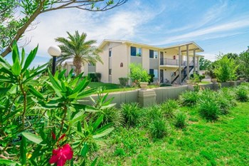 Exterior with tan building and green tropical landscaping.